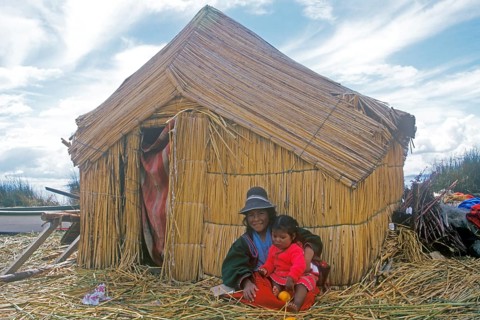 Children sitting in front of a reed hut on a floating Uro island in Lake Titcaca, Peru, South