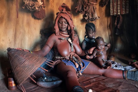 Himba woman sitting with baby, Himba perfume, scented smoke from burning plants, Himba village,