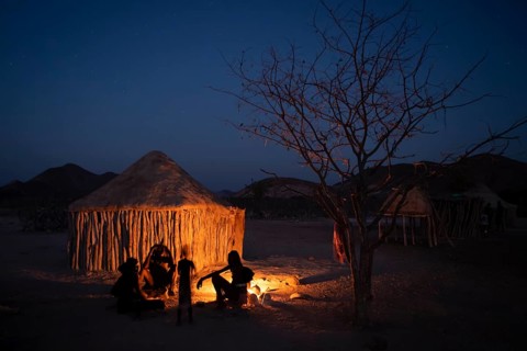 Himba at the campfire in the evening, night view, Himba huts, traditional Himba village in the