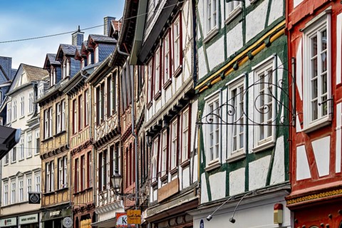 A series of half-timbered houses in various colors that form a lively street scene, The historic