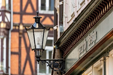 Nostalgic lantern next to a building in front of half-timbered buildings and windows in urban
