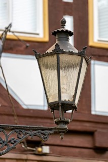 Nostalgic lantern in front of a half-timbered house with windows in a traditional cityscape, The