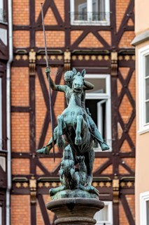 Bronze equestrian statue in front of half-timbered houses in urban surroundings, medieval flair,