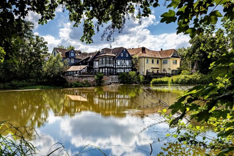 Half-timbered houses on the lakeside with blue sky and clouds, surrounded by trees, The historic
