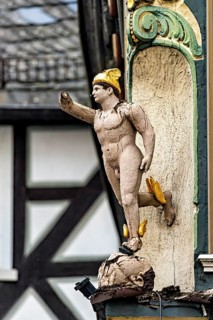 An ornate wooden statue in Roman style as building decoration, gilded details, historic and