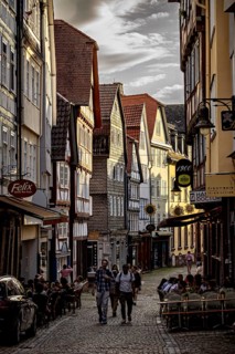 A lively street scene at sunset with people sitting at cafés in the old town, The historic old town