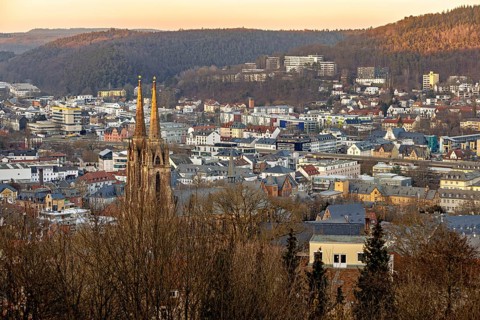 View of a town with a church and surrounding hills at sunset, view of the city of Marburg with the