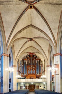 Impressive church interior with Gothic arches and imposing organ, atmospherically illuminated,