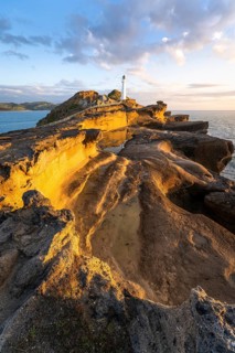 Castlepoint lighthouse on a rock, sea, sunrise. Castlepoint, Wairarapa Coast, Wellington Region,