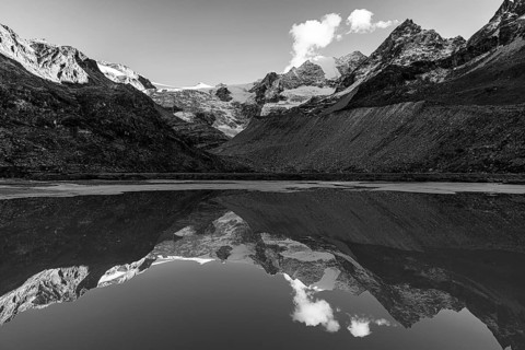 The Moiry glacier and mountain peaks are reflected in Lac de Chateaupre, black and white photo, Val