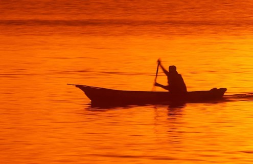 Silhouette of a fisherman in his boat at sunrise near Mikadi Beach, Dar es-Salaam, Tanzania,