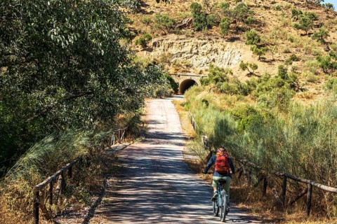 Woman riding a bycicle, cycle path Via Verde de la Sierra, path leads through a tunnel, Puerto