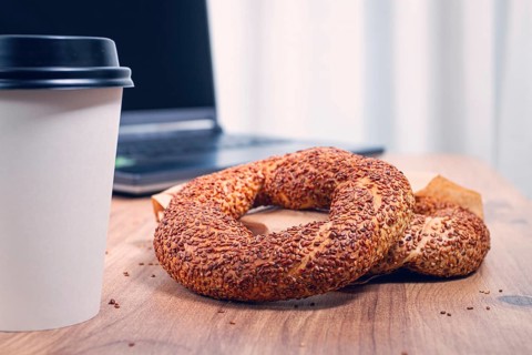 Simits with coffee on a wooden table, with a laptop, in a cozy working environment, snack,