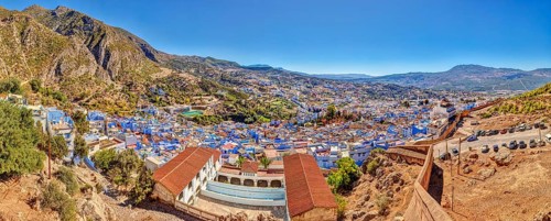 Panoramic picture of a city with distinctive blue buildings and mountainous surroundings, Morocco,