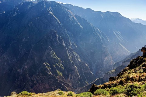 Deep canyon surrounded by high mountains in sunlight with shady areas, the mountains and valleys of