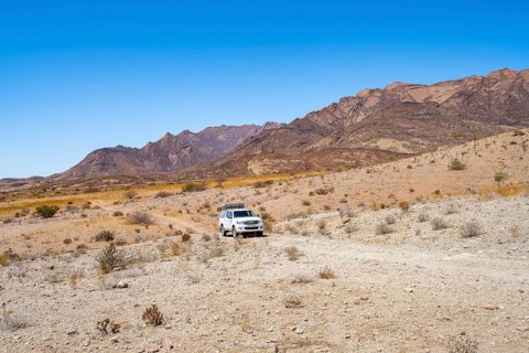Toyota Hilux off-road vehicle on a sandy track, desert landscape with Brandberg, Erongo,