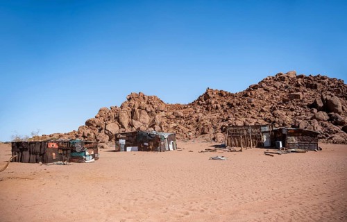 Simple poor huts made of corrugated iron and wood, desert landscape, barren landscape with hills of