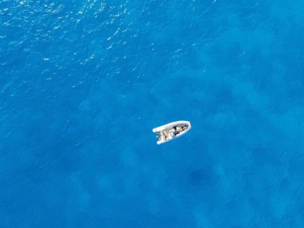 Young woman and young man lying in a motor boat on a blue sea, top-down, aerial view, Golfo di