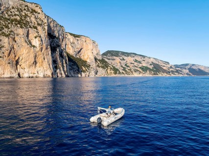 Motorboat off picturesque rocky coast ImmorgenLicht, cliffs, Golfo di Orosei, Baunei, Sardinia,