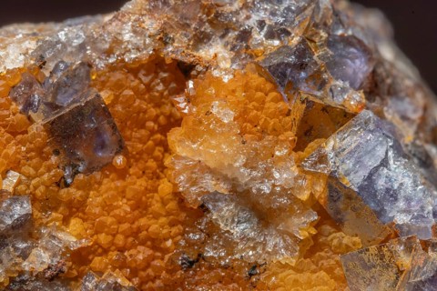 Shiny crystals of blue and orange color can be seen in this mineral formation. They are sparkling