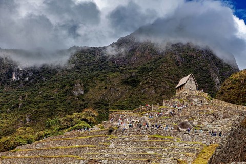Stone structures on steep terraces in front of a cloudy mountain, The ruins of the Inca city of
