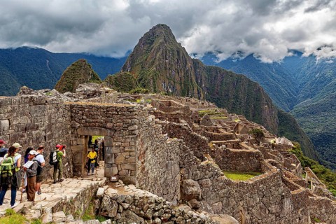 Visitors enter the ancient ruins of Machu Picchu under cloudy skies, The ruins of the Inca city of