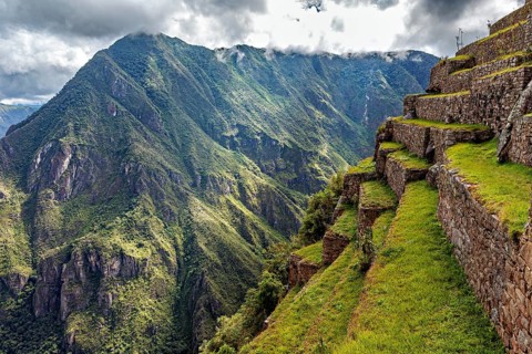 Stone terraces along a slope with spectacular panoramic views of the green mountains, the ruins of
