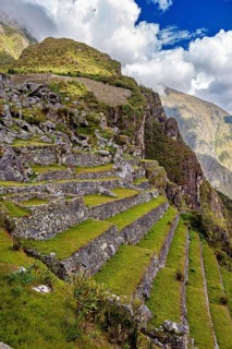 Terraces with rocky rocks and mountain formations surrounded by green and cloud-covered skies, The