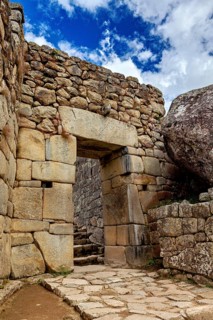 Inca stone archway with blue sky and some clouds, The ruins of the Inca city of Machu Picchu in