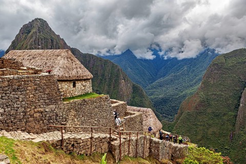 Historic ruins with grass-covered huts in the Andes against a cloudy sky, The ruins of the Inca
