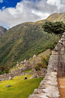 Stone terraces of Machu Picchu with surrounding green hills and blue sky, The ruins of the Inca