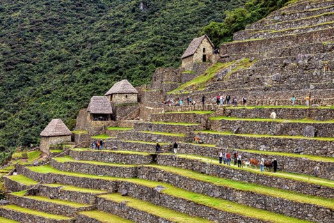 Stone houses and terraces of Machu Picchu filled with tourists and trees, The ruins of the Inca