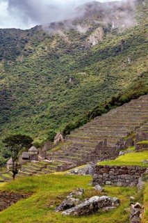 Terraces with ruins on green hills against a cloudy sky, The ruins of the Inca city of Machu Picchu