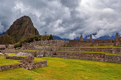 Ancient ruins against a dramatic sky with dark clouds and green areas, The ruins of the Inca city