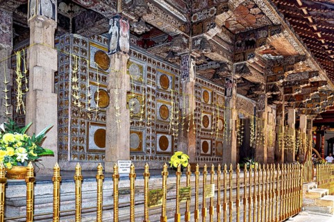 Richly decorated temple structure with ornate columns, golden ornaments and floral decorations in a
