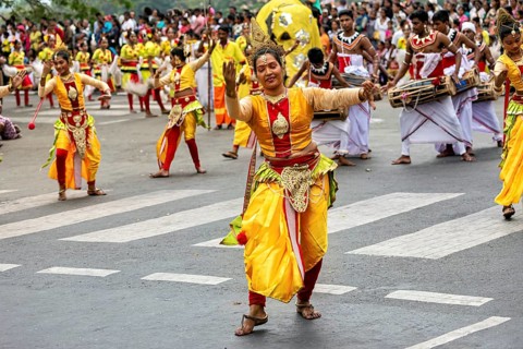 Woman in glowing traditional costume dances joyfully at a cultural parade, The Perahera Parade in