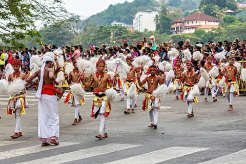 Children in festive dance costumes move happily through the streets, watched by spectators, The