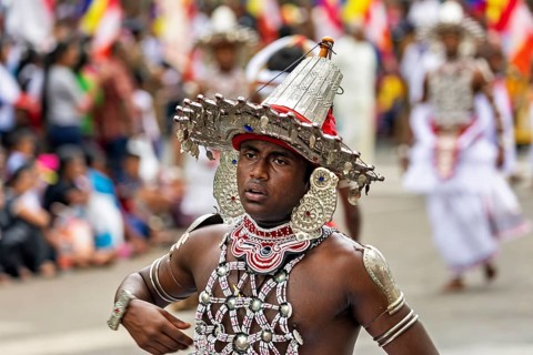 Close-up of a man wearing an elaborate, traditional headdress at a parade, The Perahera Parade in