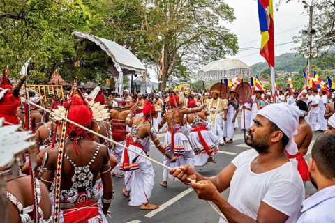 Dancers in moving costumes with flags and drums at a street festival, The Perahera Parade in Kandy