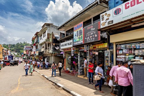 Busy shopping street with shops and passers-by under a cloudy sky in an urban setting, The shopping