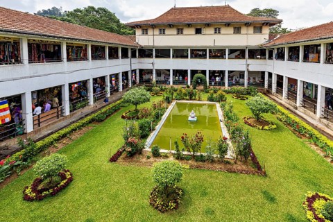 A well-kept courtyard with a central fountain and surrounding flower beds in a historic building,