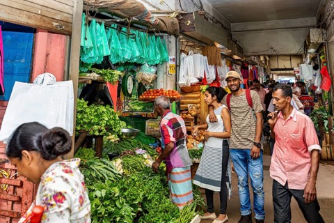 Customers and sellers in a lively vegetable stand at a market, dealers in the market halls of Kandy