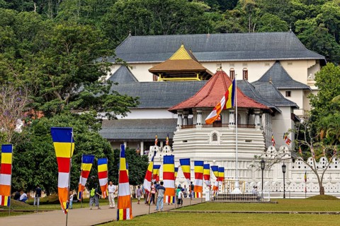 Historic building with colorful flags and group of visitors in a green setting, The Temple of the