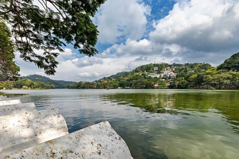 Painting of a calm lake surrounded by green hills and trees under a partly cloudy sky, Lake Kandy