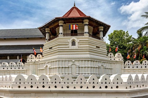 Detail of a temple with pavilion, colorful flags and white walls, The Temple of the Tooth in Kandy