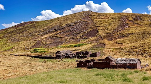 Ruins on a hill in a grassy landscape under a cloudy sky, The landscape in the highlands of Peru