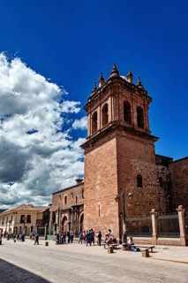 Distinctive bell tower and wall on a busy street under blue sky with clouds, The churches of Cusco