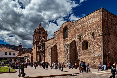 Classic church structure with a passing crowd against a dramatic cloudy sky, The churches of Cusco