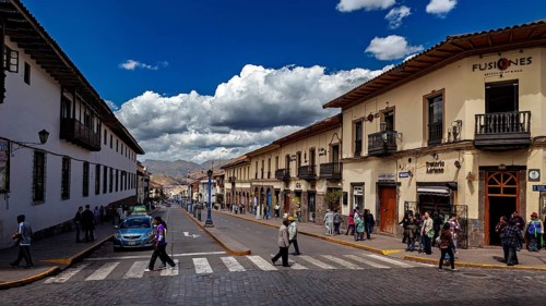 Busy street in a city with colonial architecture under a cloudy sky, The streets of Cusco in Peru