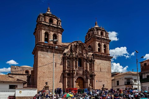 Impressive cathedral with decorated towers surrounded by a lively crowd and a clear sky, The